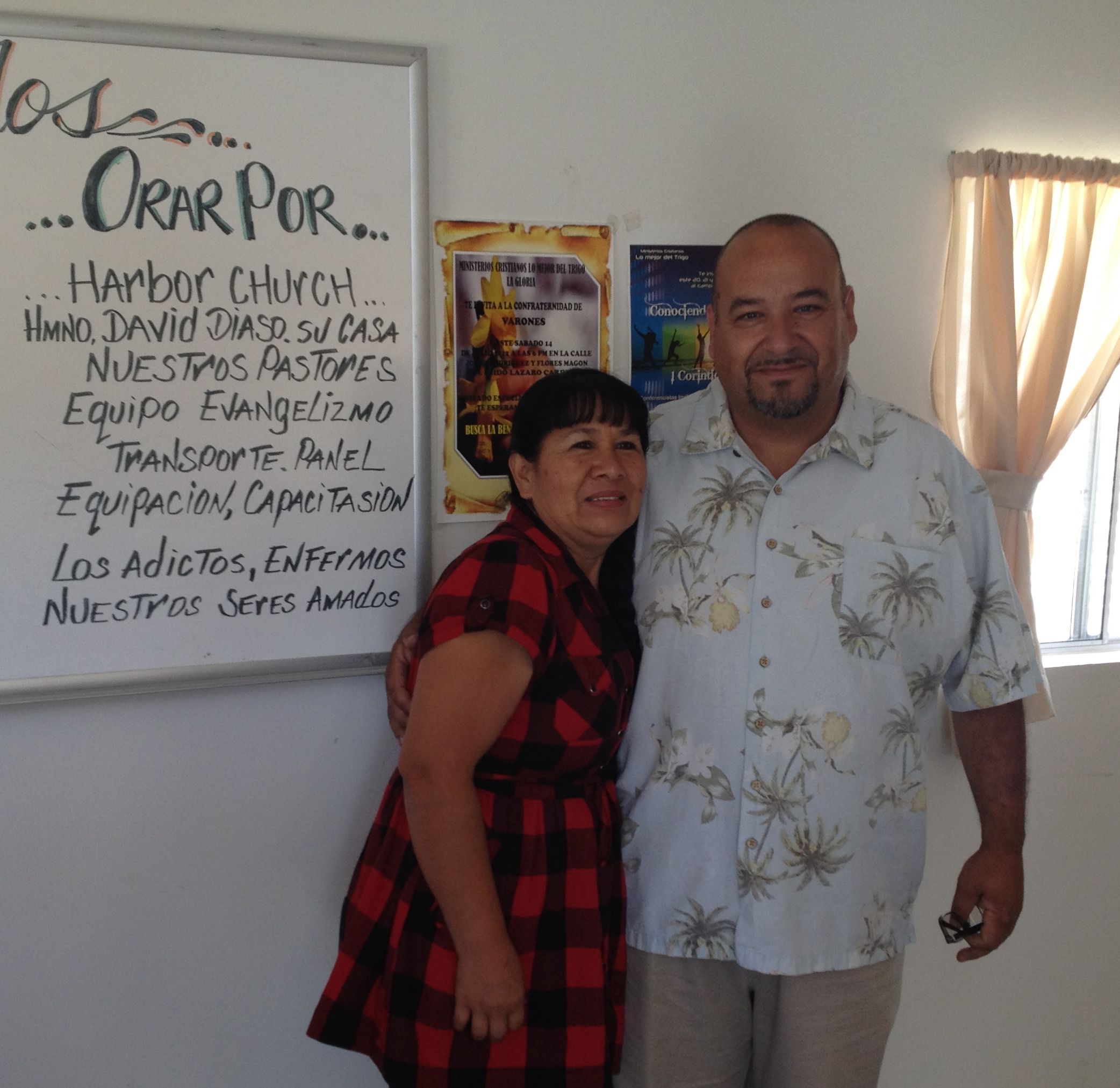 Pastor Leo and Gloria in front of the sign to pray