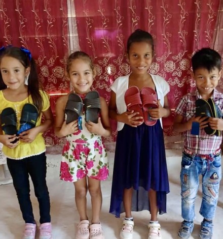 The children are all smiles receiving the sandals Yaima got them.