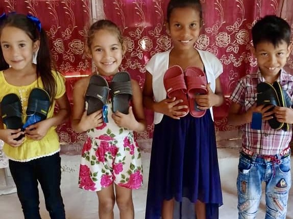 The children are all smiles receiving the sandals Yaima got them.