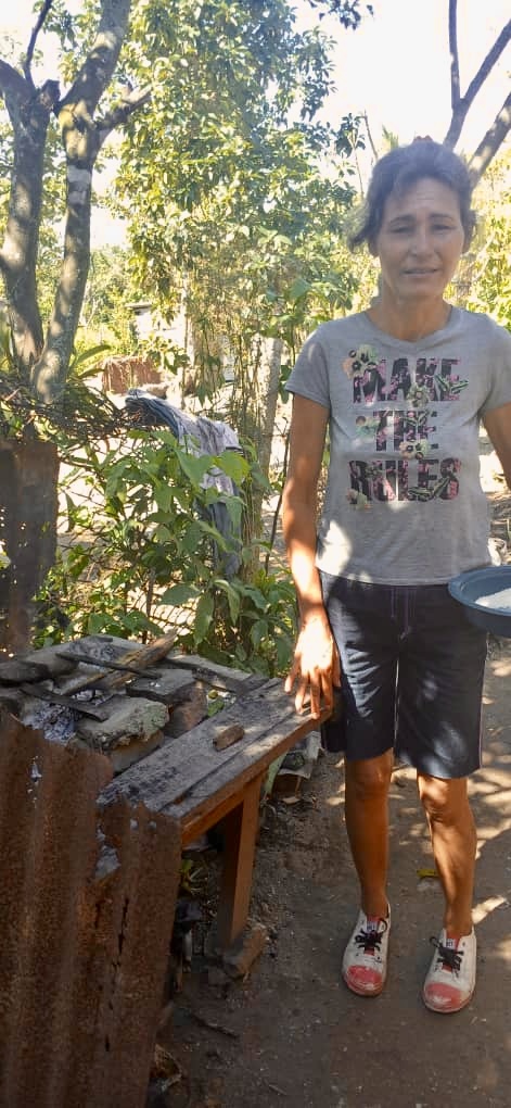 Single mother cooking outside with firewood.