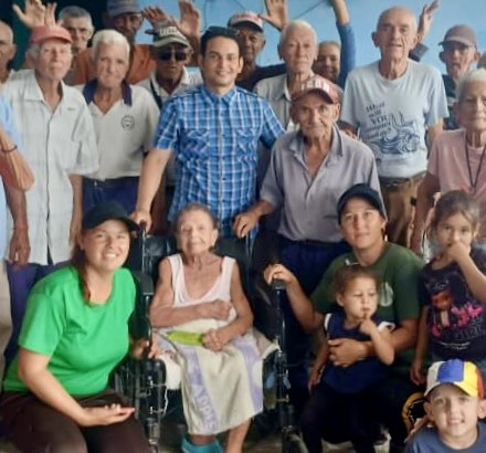 Yaima and a group of elderly people receiving a meals and aid.