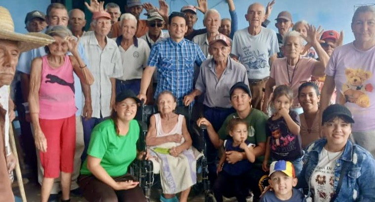 Yaima and a group of elderly people receiving a meals and aid.