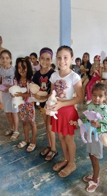 Happy faces of children receiving a toy and the message of Christ.