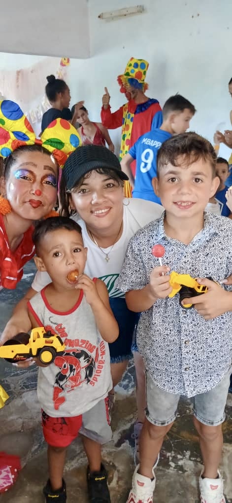 Yaima and Lety the Clown with children receiving their toys from Hannah's Toys of Hope.
